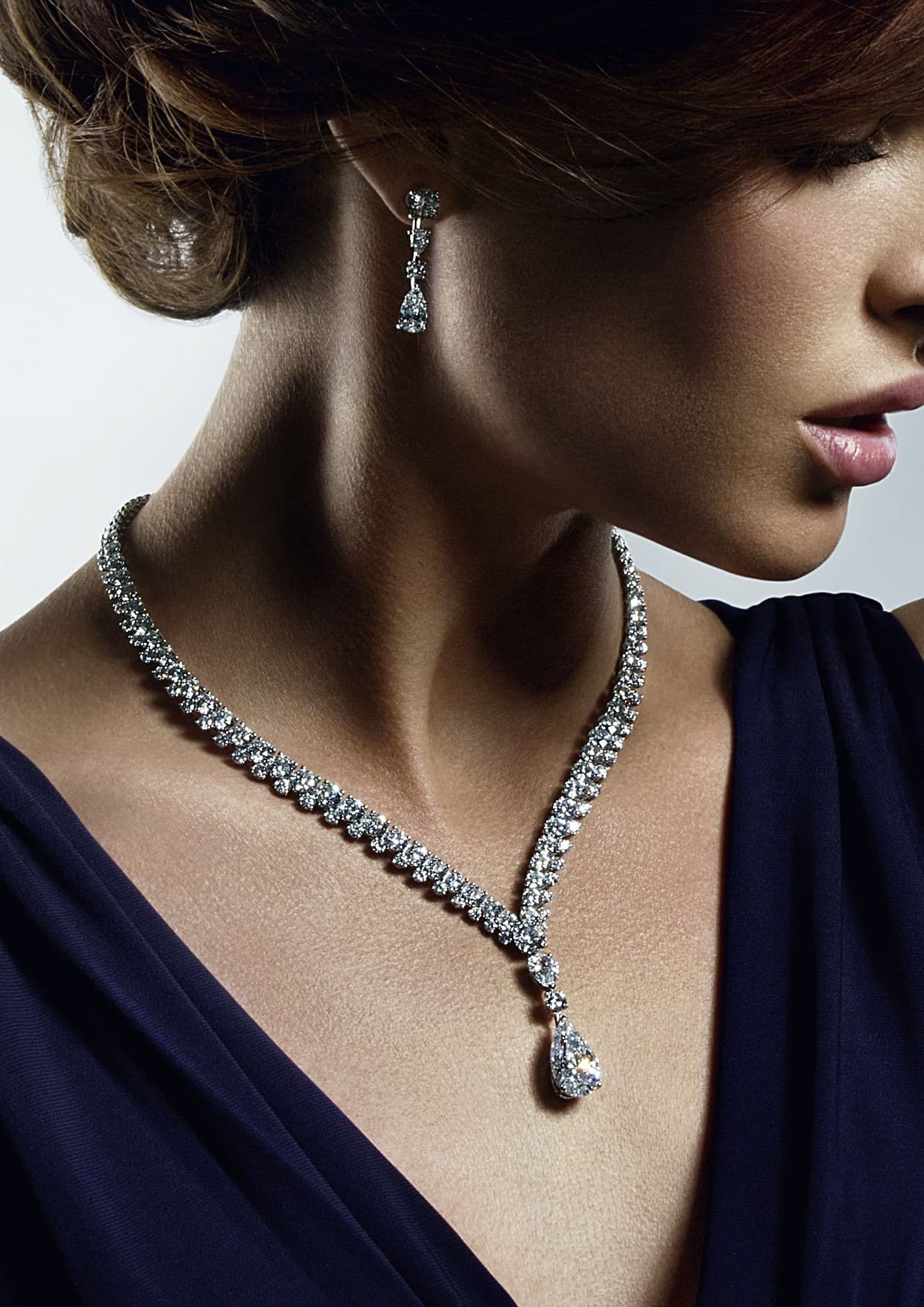 A diamond drop necklace and matching earring worn by a model